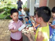 Bé Trần Anh Minh, học sinh SGA cơ sở Tô Vĩnh Diện đang tặng quà cho các bạn tại Làng thiếu nhi Quận Thủ Đức.