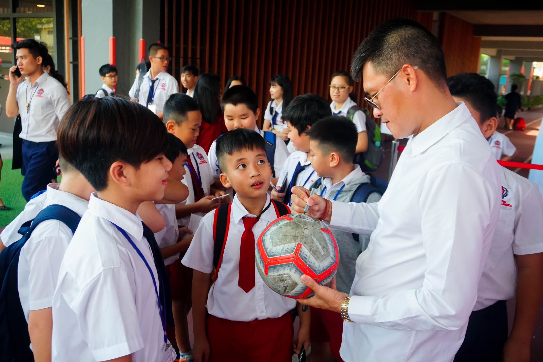 SNA students bringing their football ball to Cong Vinh to receive the signature.