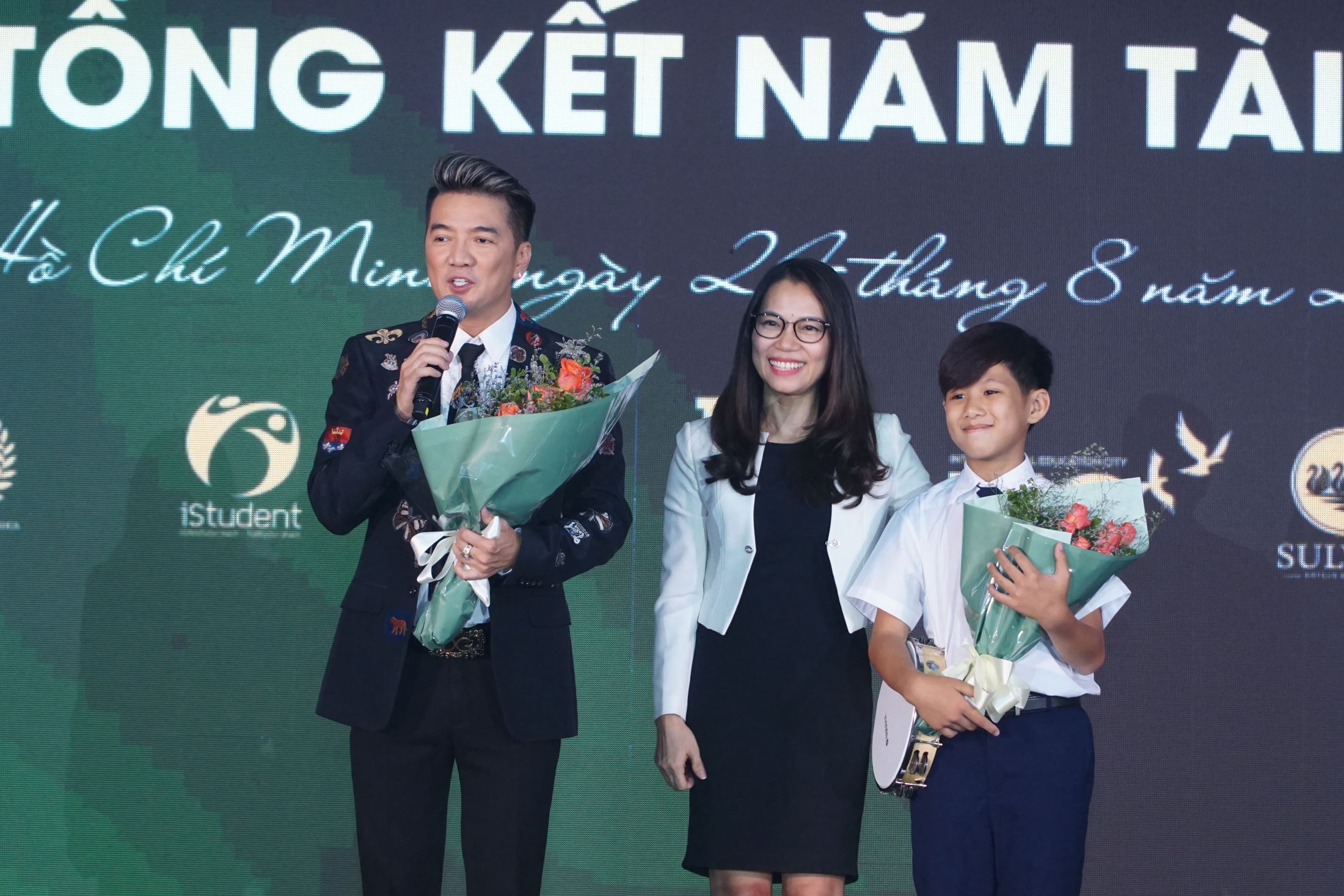 Ms. Tran Thuy Tram Quyen - Director of Branding & Communications Department gave flowers to Singer Dam Vinh Hung and Hieu Trung - parents and student of SNA.