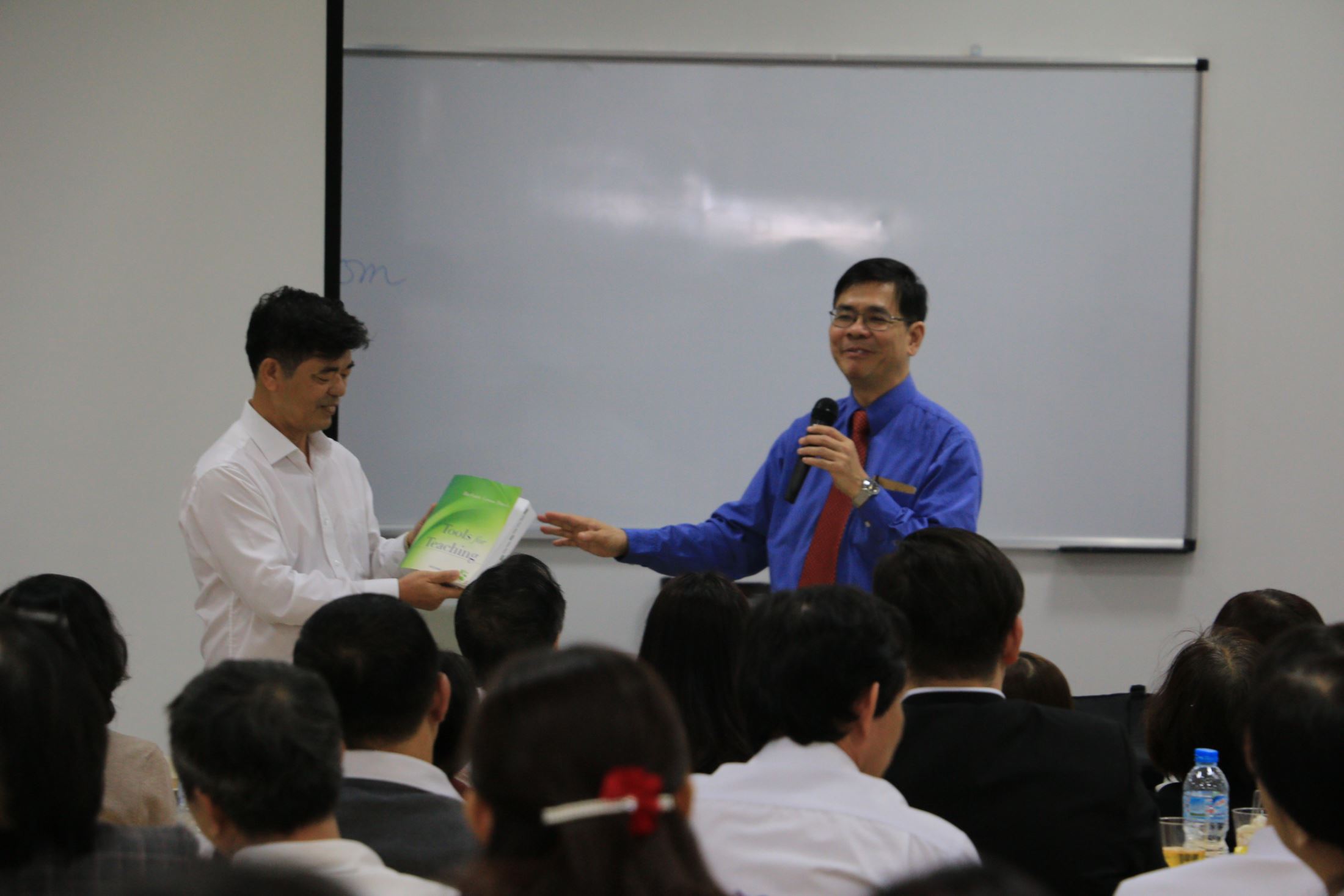 Assoc. Prof. Dr. Thai Ba Can, Principal of HIU to receive a book from Prof. Le Xuan Hy on behalf of HIU staff and student